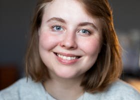 A cheerful woman with short blonde hair smiling indoors, showcasing natural beauty.
